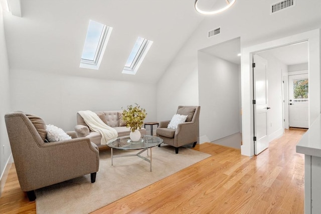 sitting room featuring vaulted ceiling with skylight, visible vents, and light wood-style flooring