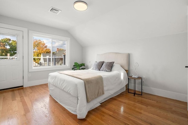 bedroom with visible vents, baseboards, lofted ceiling, and wood finished floors