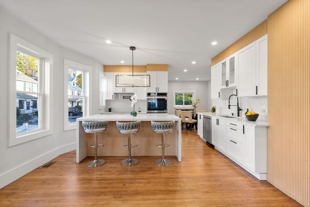 kitchen featuring tasteful backsplash, light wood-style flooring, a kitchen bar, and a sink