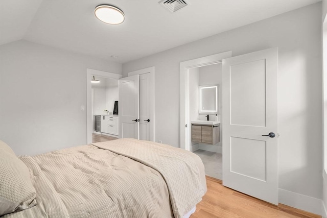 bedroom featuring light wood finished floors, visible vents, connected bathroom, and baseboards