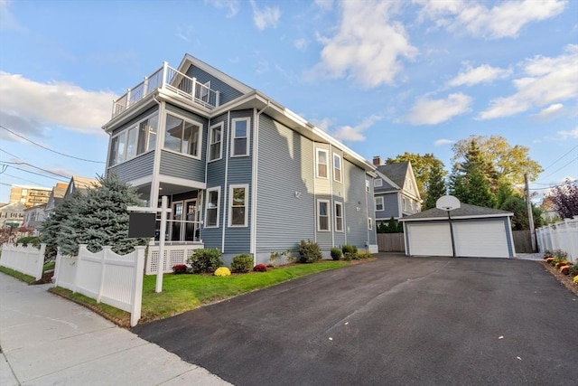 view of side of property featuring a garage, an outdoor structure, a balcony, and fence