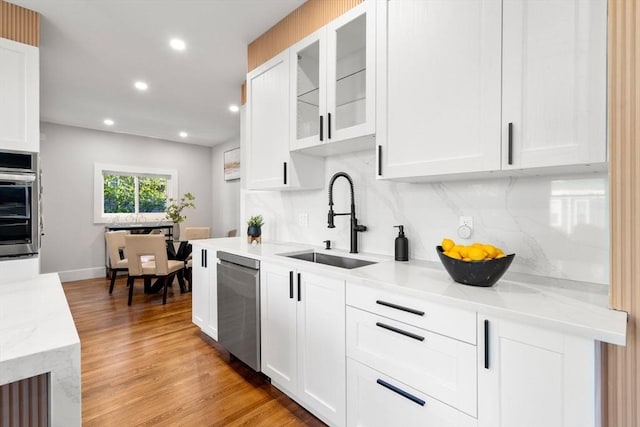 kitchen featuring a sink, glass insert cabinets, white cabinetry, and stainless steel appliances