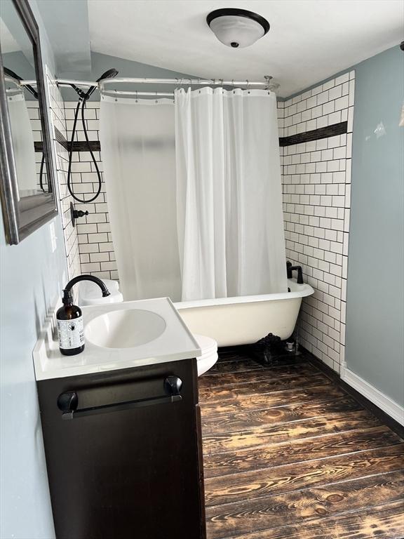 bathroom featuring hardwood / wood-style flooring, vanity, and shower / tub combo with curtain