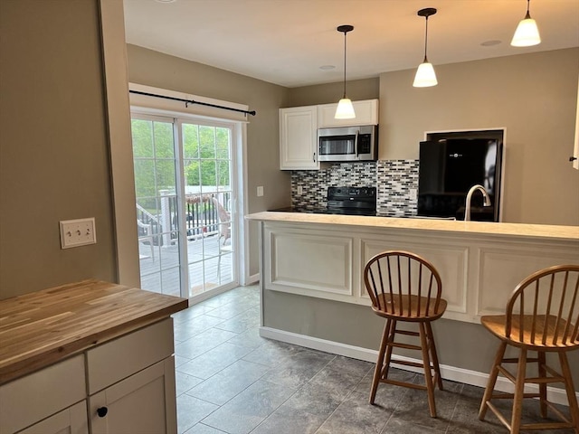 kitchen with white cabinetry, sink, backsplash, hanging light fixtures, and black appliances