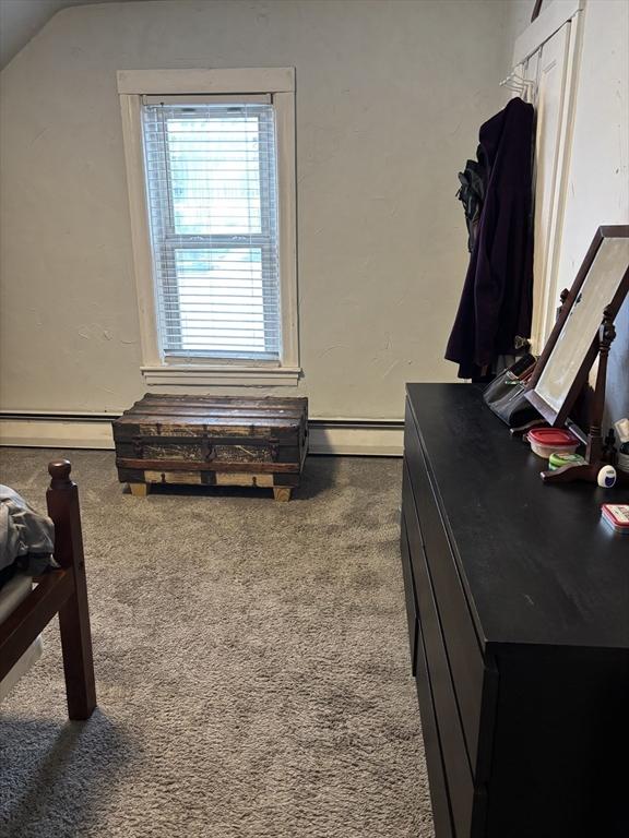 carpeted bedroom with lofted ceiling and baseboard heating