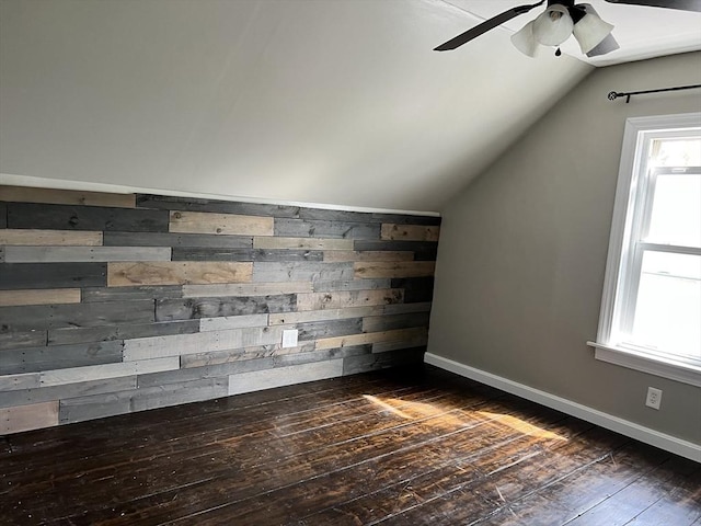 bonus room featuring dark hardwood / wood-style flooring, vaulted ceiling, ceiling fan, and wood walls