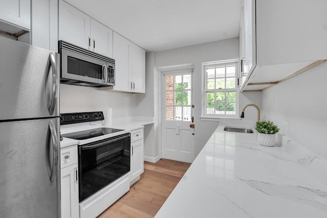 7 Hammond Pond Pkwy Unit 1, Newton, MA 02467 - kitchen featuring stainless steel appliances, white cabinetry, light wood finished floors, a sink, and light stone countertops