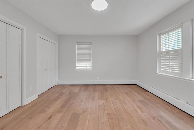 7 Hammond Pond Pkwy Unit 1, Newton, MA 02467 - unfurnished bedroom featuring two closets, light wood finished floors, a baseboard radiator, and baseboards