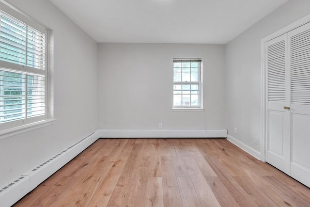 7 Hammond Pond Pkwy Unit 1, Newton, MA 02467 - unfurnished bedroom featuring light wood-style flooring, baseboard heating, baseboards, and a closet
