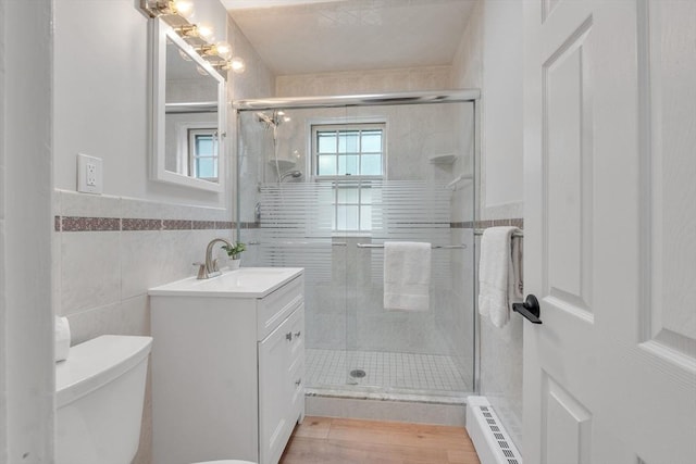 7 Hammond Pond Pkwy Unit 1, Newton, MA 02467 - bathroom featuring baseboard heating, vanity, toilet, a shower stall, and tile walls