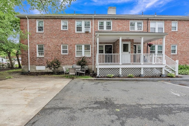 7 Hammond Pond Pkwy Unit 1, Newton, MA 02467 - view of front of home featuring a porch, a chimney, brick siding, and cooling unit