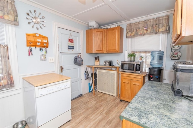 kitchen featuring stainless steel microwave, light countertops, dishwasher, ornamental molding, and light wood finished floors