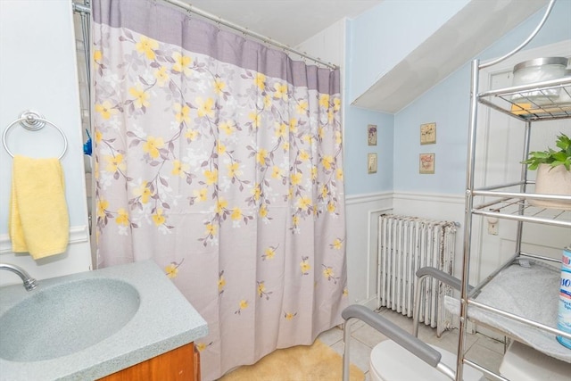 full bathroom featuring radiator heating unit, curtained shower, toilet, and a wainscoted wall