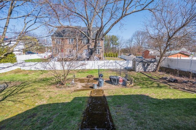 view of yard with a storage unit, an outbuilding, and a fenced backyard