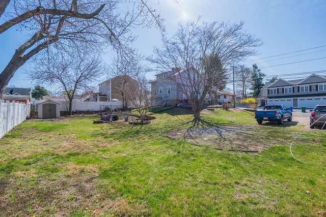 view of yard with fence, a residential view, an outbuilding, and a storage shed