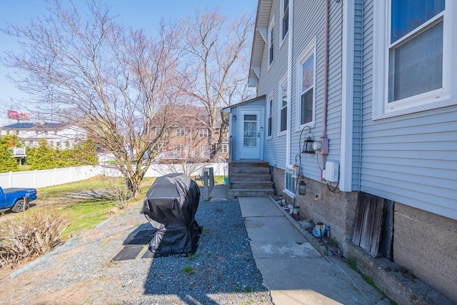 view of side of home featuring entry steps and fence