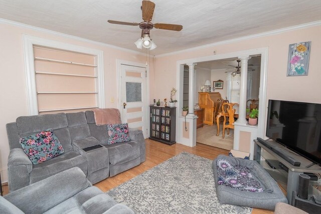 living room featuring ornamental molding, a ceiling fan, light wood-style flooring, and decorative columns
