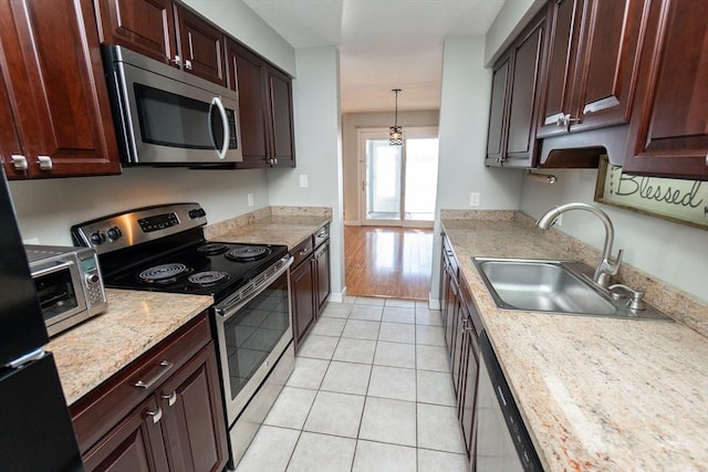 kitchen featuring sink, light tile patterned floors, appliances with stainless steel finishes, hanging light fixtures, and light stone countertops