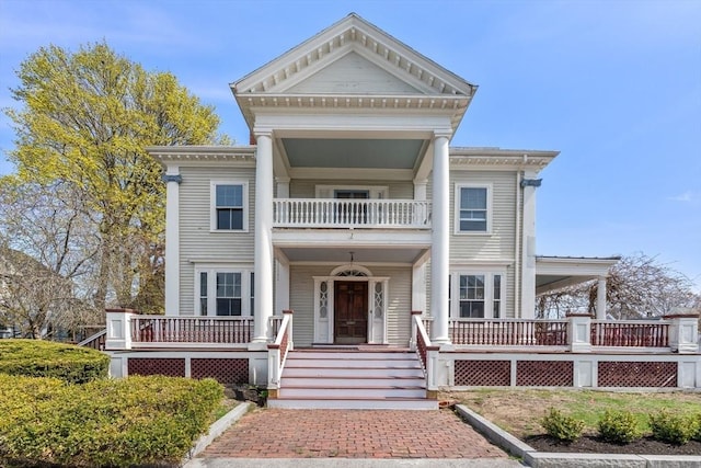 greek revival inspired property with a balcony and covered porch