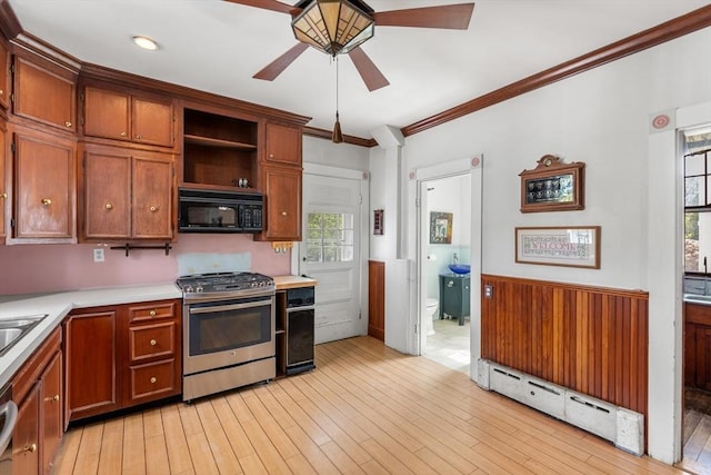 kitchen with stainless steel range with gas cooktop, black microwave, ceiling fan, light countertops, and ornamental molding