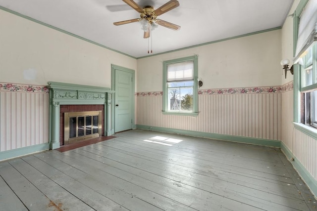 unfurnished living room featuring a wealth of natural light, hardwood / wood-style flooring, a fireplace, and ceiling fan