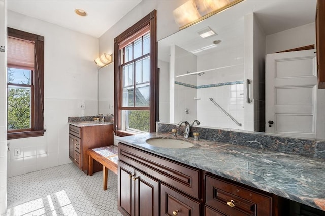 full bath featuring tile walls, plenty of natural light, vanity, and a shower