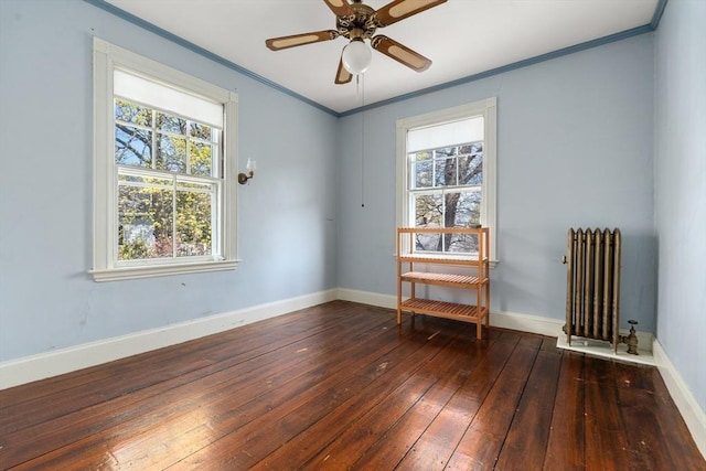empty room featuring radiator heating unit, a healthy amount of sunlight, ornamental molding, and wood-type flooring