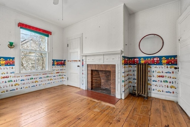 unfurnished living room featuring hardwood / wood-style floors, wallpapered walls, baseboards, and ornamental molding