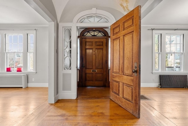 foyer featuring baseboards, radiator heating unit, and light wood-style floors
