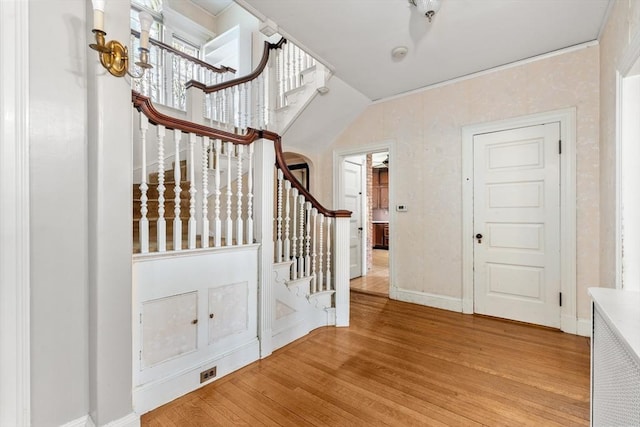 entryway featuring light wood-style flooring, baseboards, and stairs