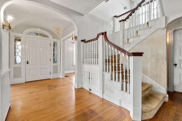 entryway with hardwood / wood-style flooring, baseboards, arched walkways, and stairs