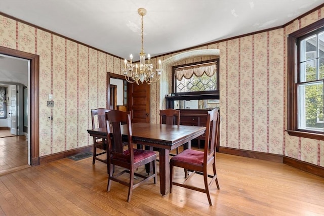 dining area featuring hardwood / wood-style floors, wallpapered walls, baseboards, and an inviting chandelier