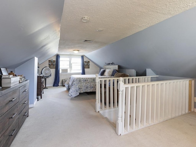 bedroom featuring vaulted ceiling, light colored carpet, and a textured ceiling