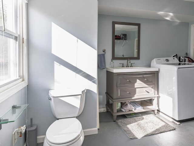 half bathroom with washer / clothes dryer, healthy amount of natural light, concrete floors, and toilet