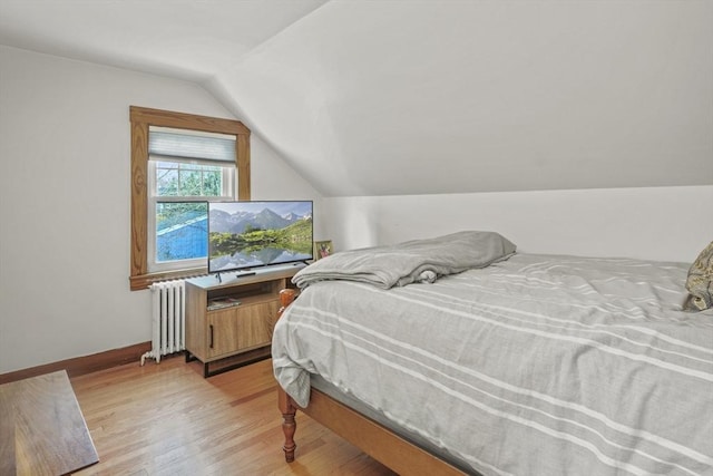 bedroom with baseboards, lofted ceiling, radiator, and light wood-type flooring