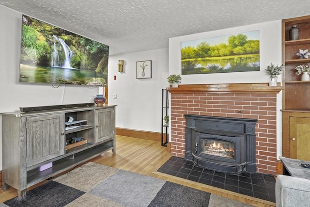 living room with a textured ceiling, baseboards, wood finished floors, and a wood stove