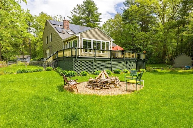 16 Gilbert Way, Millbury, MA 01527 - rear view of house with an outdoor fire pit, a lawn, solar panels, a chimney, and a wooden deck