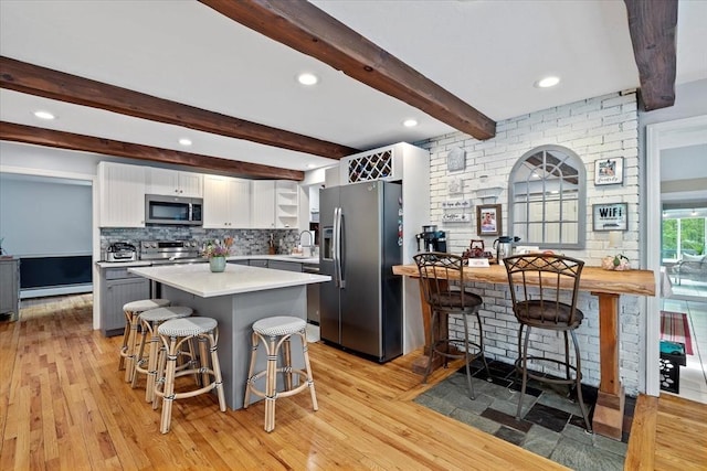 16 Gilbert Way, Millbury, MA 01527 - kitchen with stainless steel appliances, a breakfast bar area, white cabinets, light countertops, and light wood-style flooring