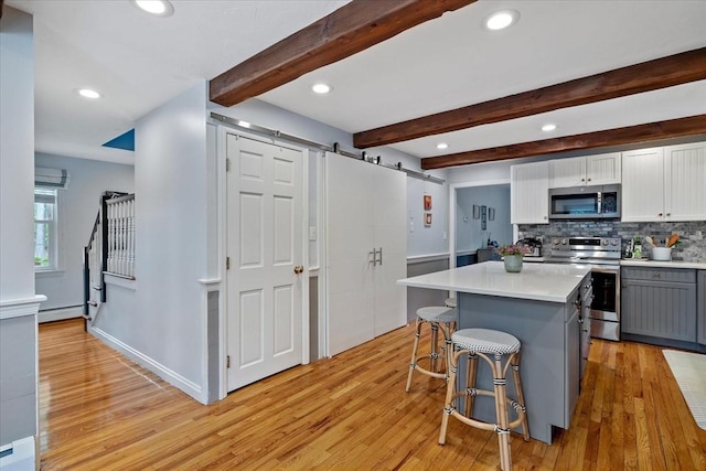 16 Gilbert Way, Millbury, MA 01527 - kitchen with appliances with stainless steel finishes, a barn door, baseboard heating, light wood-type flooring, and recessed lighting