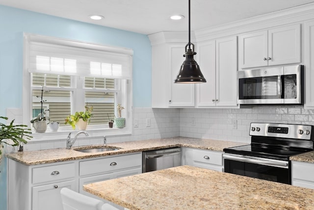 kitchen featuring appliances with stainless steel finishes, backsplash, sink, pendant lighting, and white cabinets