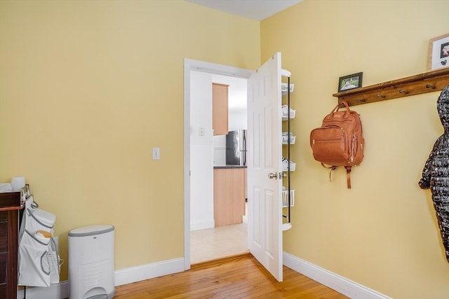 interior space featuring freestanding refrigerator, light wood-style flooring, and baseboards