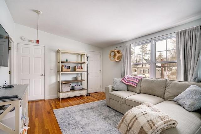 living room with vaulted ceiling, light wood finished floors, and baseboards