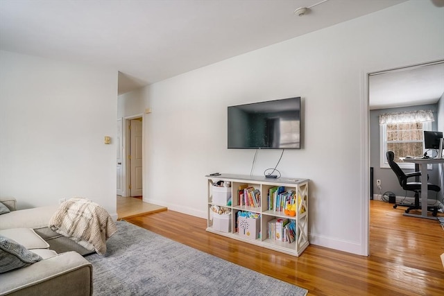 living area with baseboards and wood finished floors