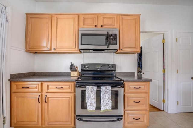 kitchen with stainless steel appliances, dark countertops, and light tile patterned floors