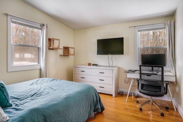 bedroom with light wood-style floors, multiple windows, and baseboards