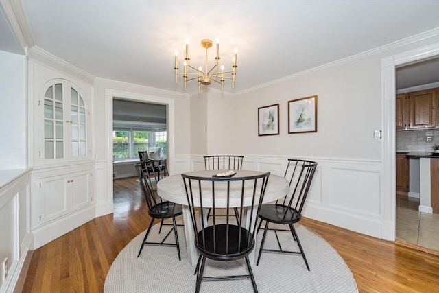 6 Gilbert Rd, Natick, MA 01760 - dining room with light wood finished floors, a chandelier, crown molding, a wainscoted wall, and a decorative wall