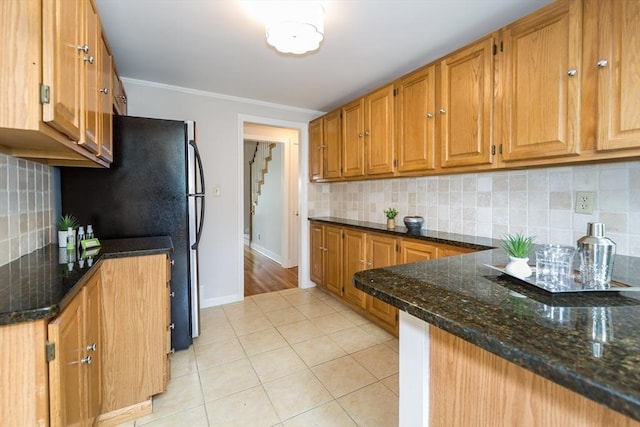 6 Gilbert Rd, Natick, MA 01760 - kitchen featuring light tile patterned floors, freestanding refrigerator, dark stone counters, baseboards, and backsplash