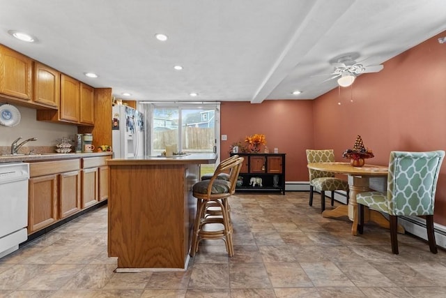 kitchen with a breakfast bar area, ceiling fan, a center island, white appliances, and sink