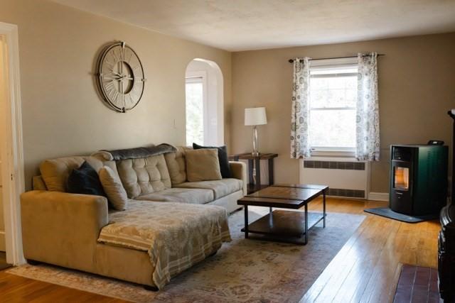 24 Congamond Rd, Southwick, MA 01077 - living room featuring baseboards, wood finished floors, arched walkways, radiator, and a wood stove