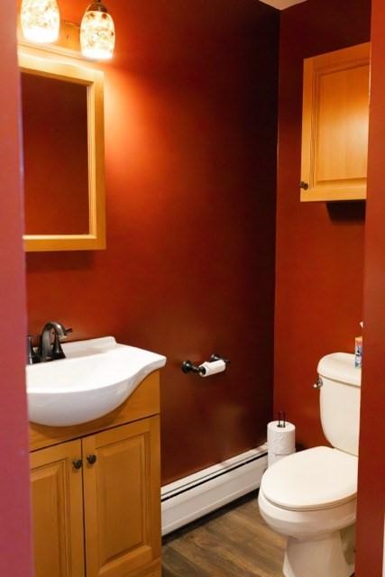 24 Congamond Rd, Southwick, MA 01077 - bathroom with toilet, wood finished floors, vanity, and a baseboard radiator